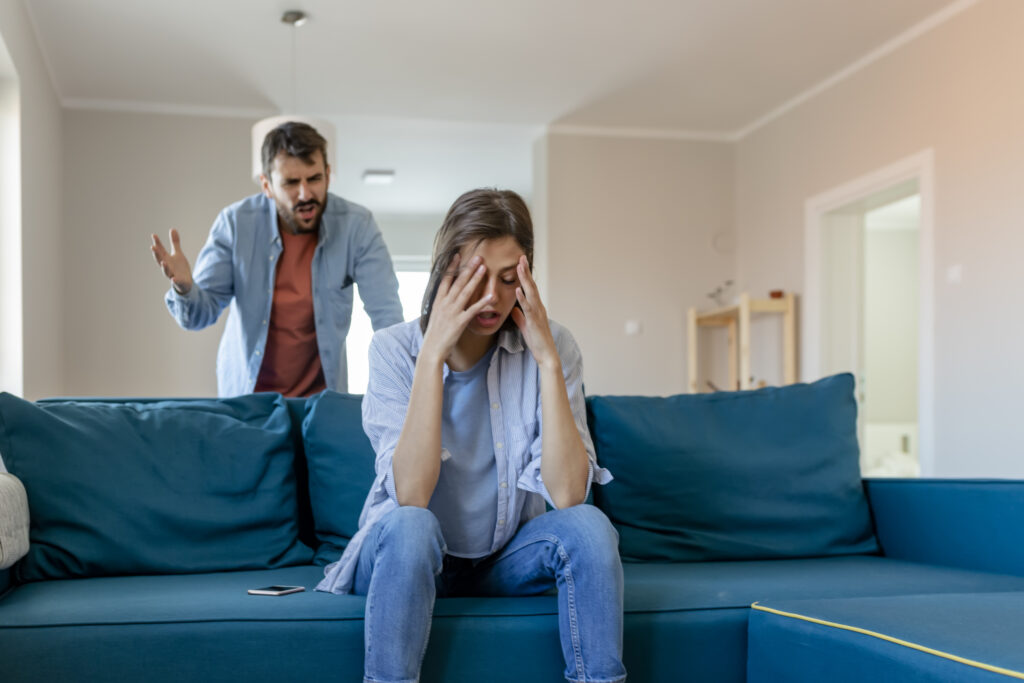 Distressed woman experiencing emotional conflict as her husband yells, highlighting relationship tension and communication issues.