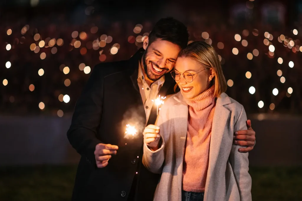 Happy couple celebrating New Year’s Eve with sparklers, symbolizing keeping New Year’s resolutions for stronger relationships through shared goals and quality time.